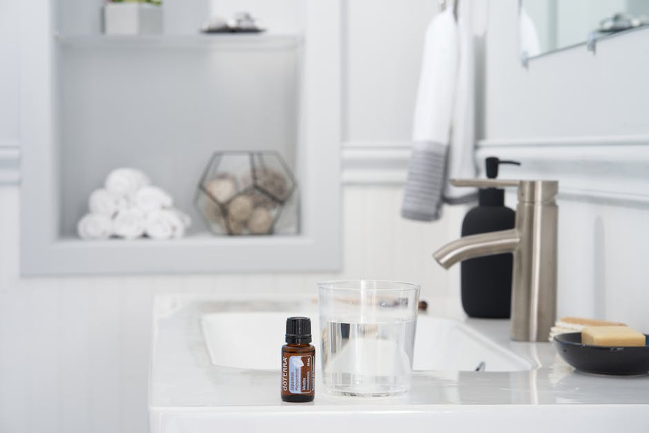 A stylish bathroom setting featuring essential oils, glass of water, and towels.