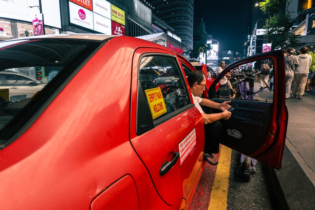 Woman entering a red taxi at night