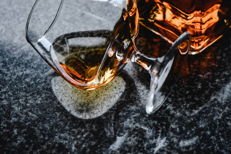 Stylish close-up of whiskey in a glass and bottle on a textured surface, perfect for beverage themes.