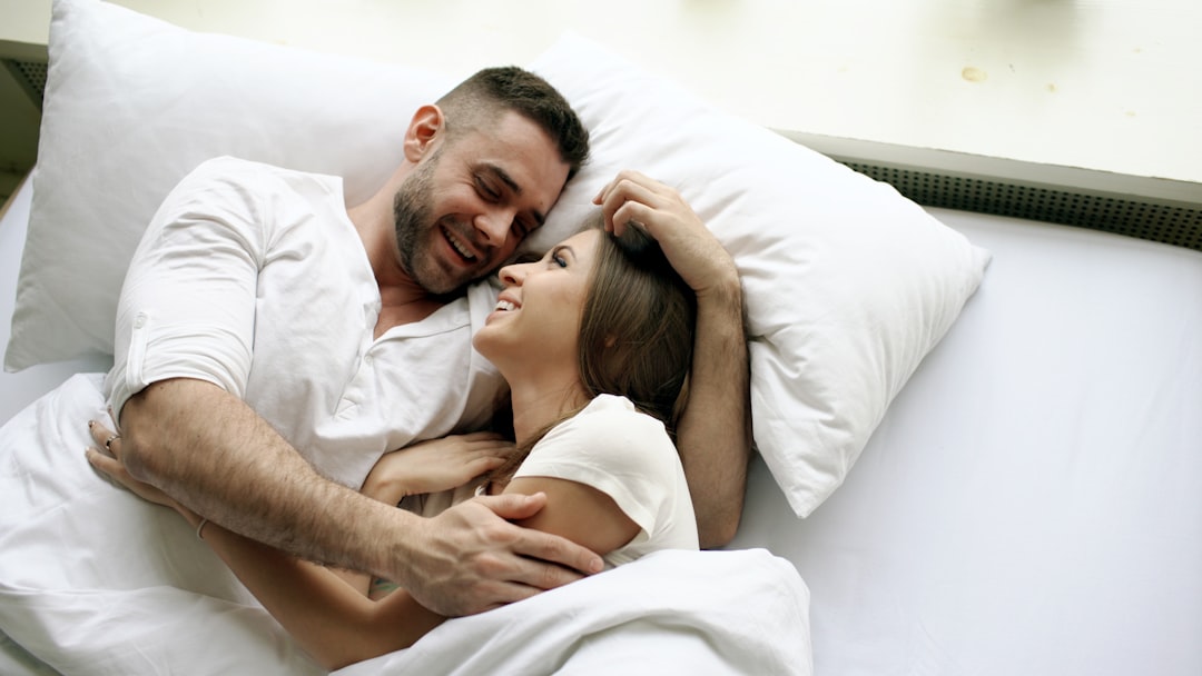 A couple embracing in bed, smiling at each other.