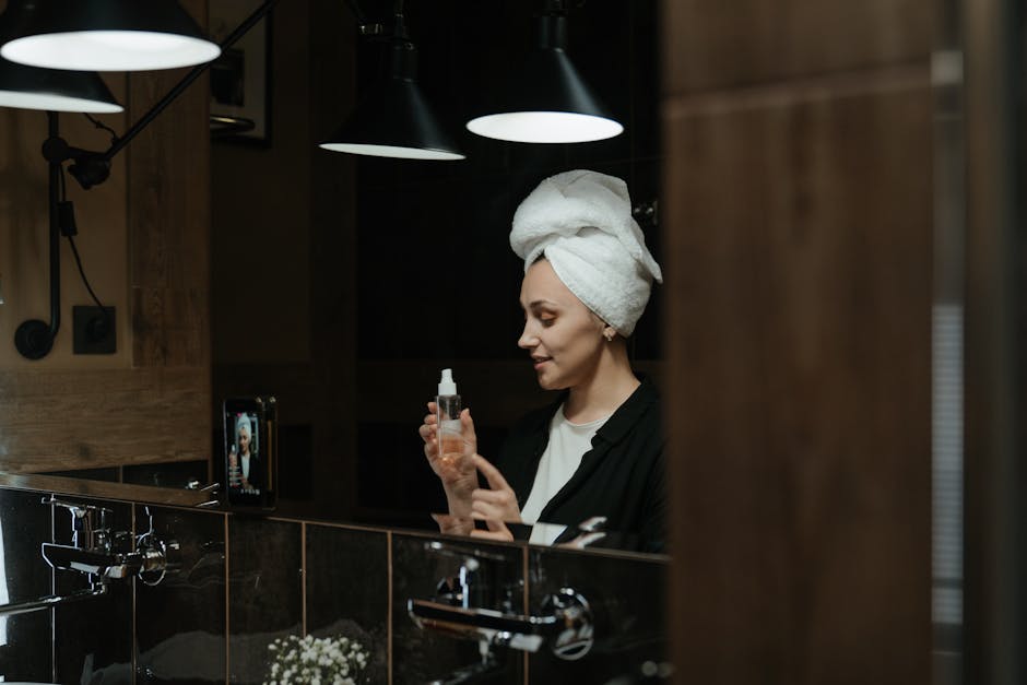 Adult woman with towel on head applying skincare product, focusing on self care routine.