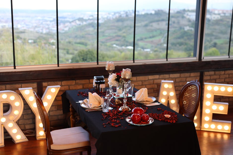 Elegant dining table with lit letters and scenic landscape view through windows.