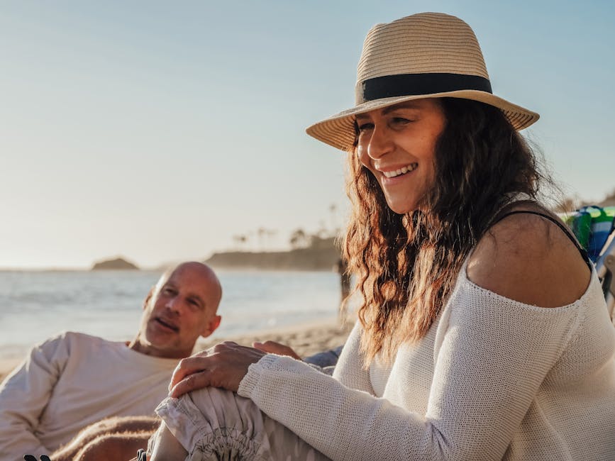 Smiling couple relaxing on the beach during a sunny day, exuding joy and tranquility.