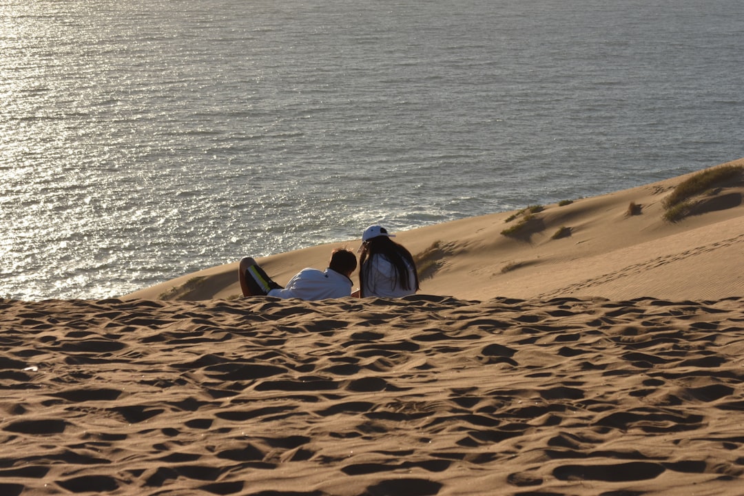 a couple of people sit on a beach