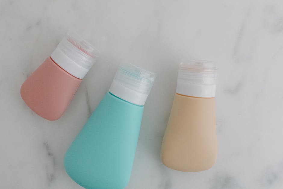 Three colorful squeezable bottles with flip tops on a marble surface.