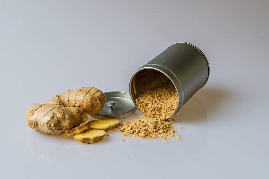 Close-up of fresh ginger root with sliced pieces and ginger powder spilled from a metal container.