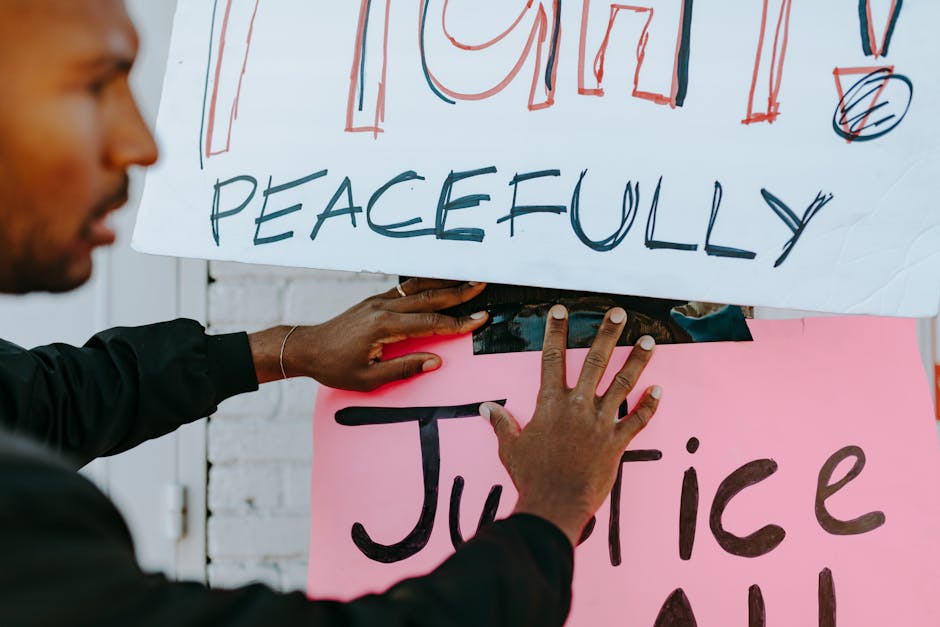 Close-up of hands holding protest signs advocating for peace and justice.