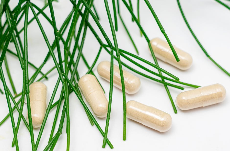 Close-up of beige capsules surrounded by green leaves on a white surface.