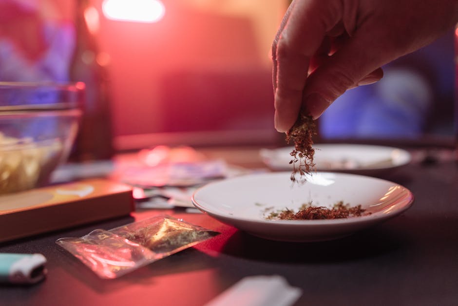 Close-up of hand sprinkling dry herbs onto saucer, indoors.