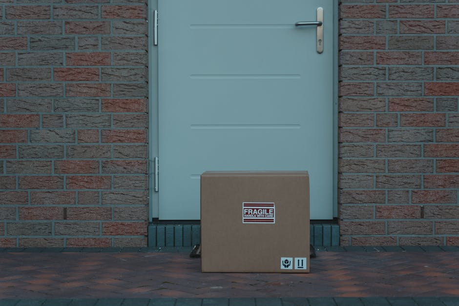 Cardboard box placed outside a brick-walled entrance, labeled fragile for delivery.