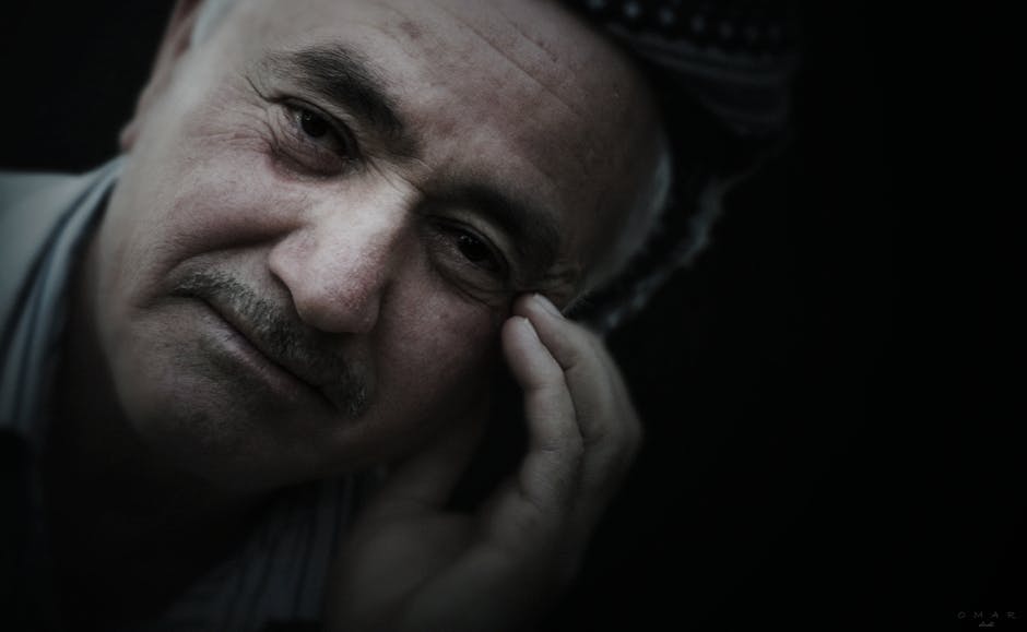 Close-up portrait of a senior man with thoughtful expression, touching his face.