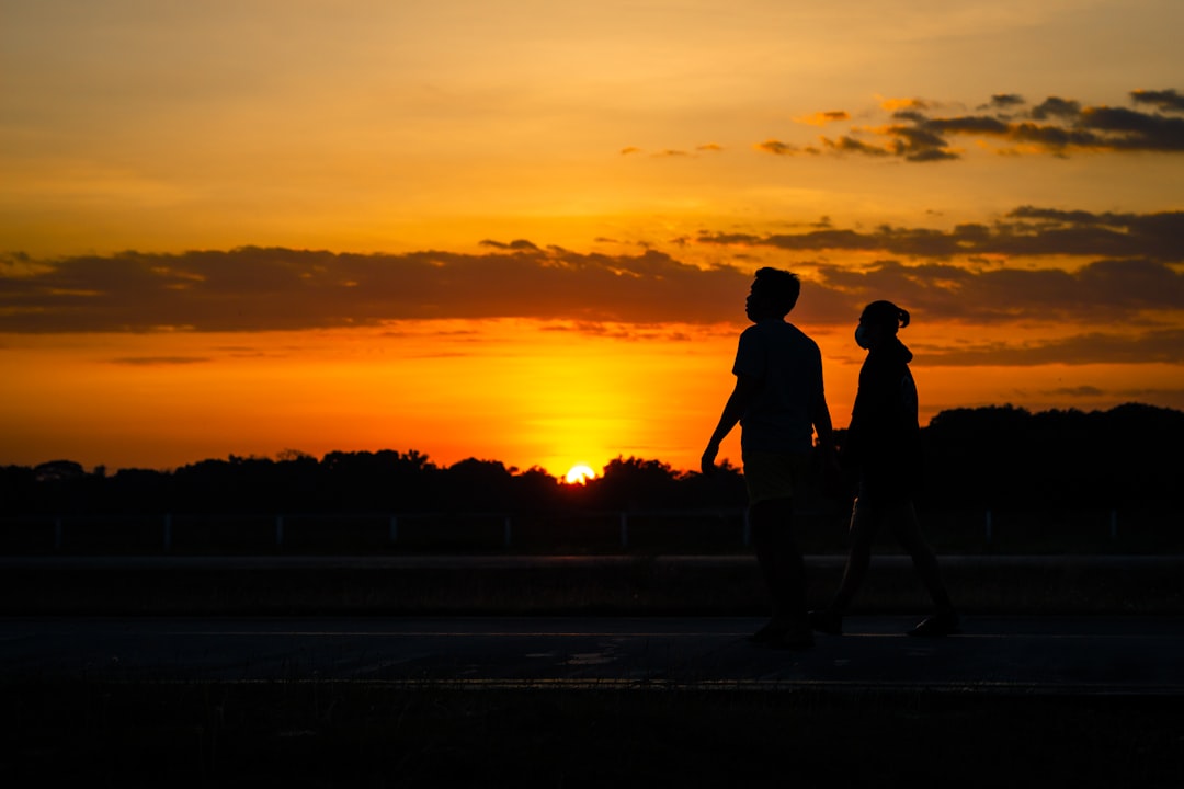 silhouette of 2 person walking on beach during sunset